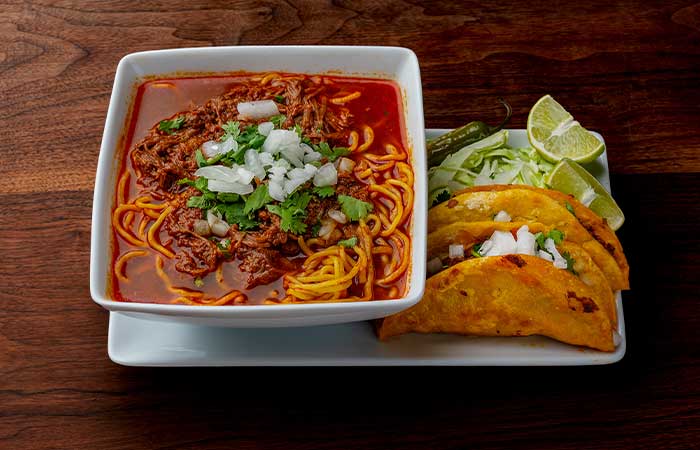 Ramen-Birria, Tacos and a bowl of ramen, with a side of lettuce, lime and a pepper